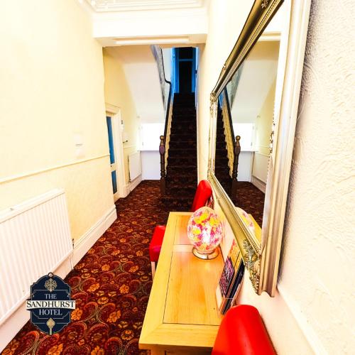 a hallway with a table and red chairs and a mirror at The Sandhurst Hotel in Blackpool