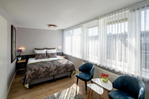 a bedroom with a bed and two chairs at Jupiter Hotel in Amsterdam