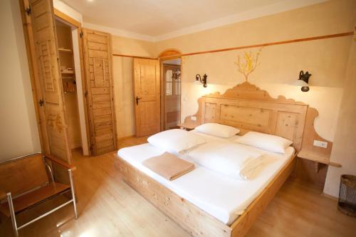 a bedroom with a large bed with white sheets at Piccolohotel Tempele Residence in San Candido