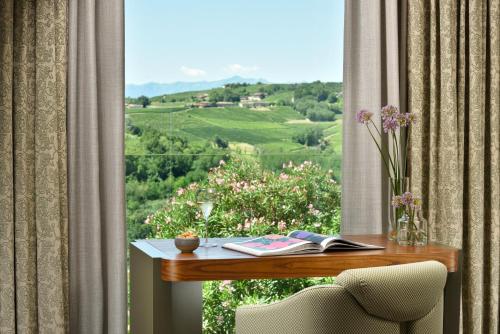 a room with a table and a window with a view at Il Boscareto Resort & Spa in Serralunga d'Alba