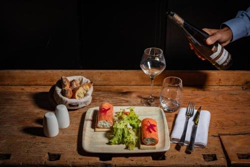 a table with a plate of food and a glass of wine at Europe Haguenau – Hotel & Spa in Haguenau