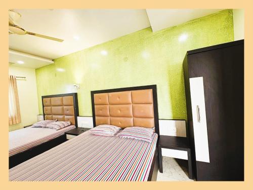 two beds in a room with green walls at Pride Pitu পিটু Near The Amrabati Park AC OR NON AC Both Facility in Digha