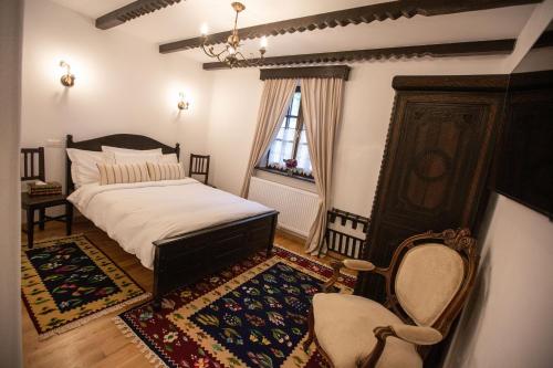 a bedroom with a bed and a chair and a window at Odaile Brancovenesti -Maldaresti in Măldăreşti