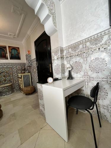 a desk and a chair in a room with wallpaper at Meyssa's Paradise in Tangier