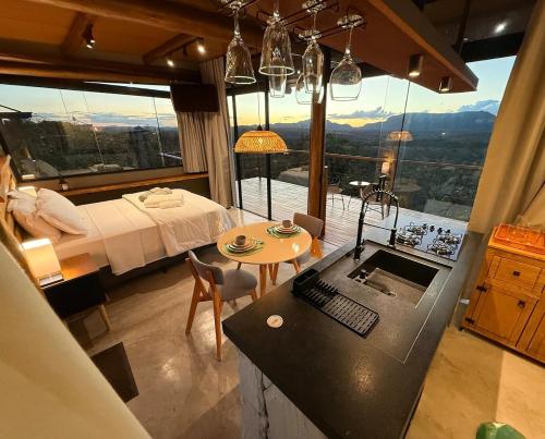 a bedroom with a bed and a kitchen with a table at Chalé Canela de Ema in Sao Jorge