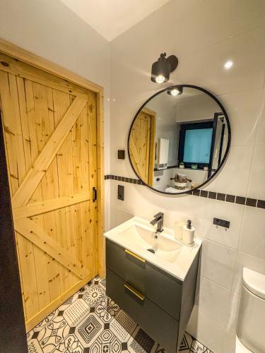 a bathroom with a wooden door and a sink and a mirror at Mazury Linowo - Domy z basenami in Linowo