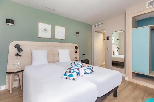 a bedroom with a large white bed and a mirror at Appart'City Confort Montpellier Saint Roch in Montpellier
