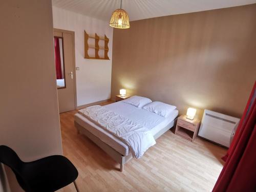 a bedroom with a bed and two tables and a chair at Grand T2 avec balcon - proche centre historique in Moutiers