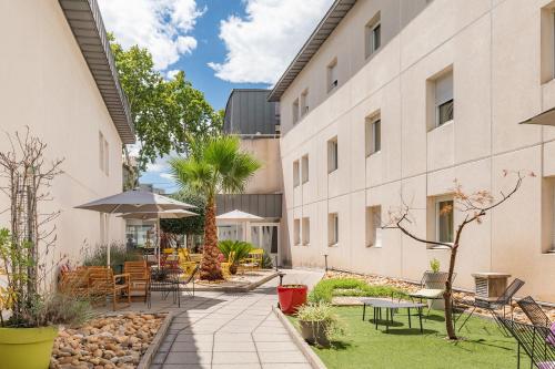 an internal courtyard of a building with tables and chairs at Appart'City Confort Montpellier Saint Roch in Montpellier