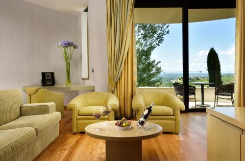 a living room with yellow furniture and a table with wine glasses at Il Boscareto Resort & Spa in Serralunga d'Alba
