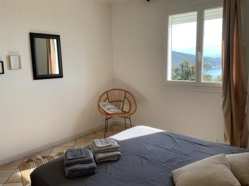 a bedroom with a bed and a chair and a window at Cap en Corse in Farinole
