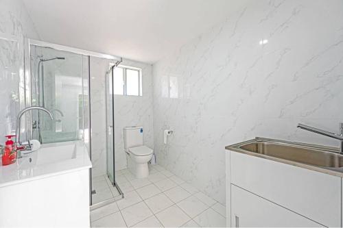 a white bathroom with a sink and a toilet at 2bd 2bth Modern House close 2Train&Westfield in Hornsby