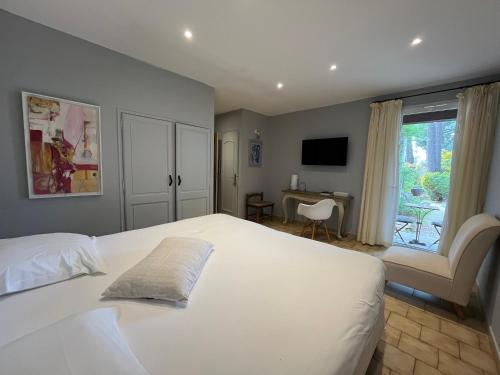 a bedroom with a large white bed and a desk at Logis Hôtel restaurant des Pins in Bédoin