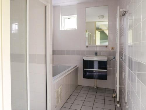 ein Badezimmer mit Badewanne, Waschbecken und Spiegel in der Unterkunft Holiday Home Bungalowpark It Wiid by Interhome in Eernewoude