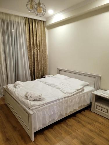 a bedroom with a bed with white sheets and a window at Stylish House in Kutaisi