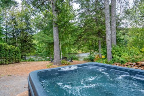 une baignoire jacuzzi dans une cour arborée dans l'établissement Spa & River - L'ecureuil, à Saint-Alexis-des-Monts