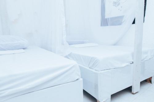 a white room with two beds and a mirror at WHITE HOUSE STAR Hotel in Malindi