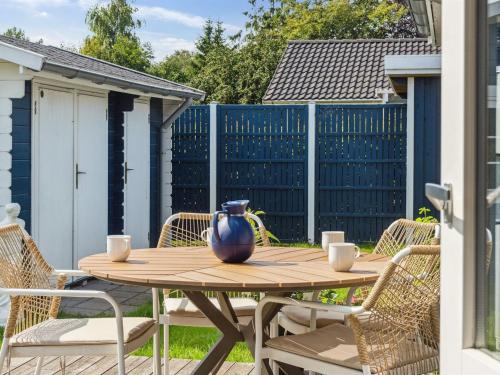 a wooden table with chairs and a vase on it at Holiday Home Asvalde - 200m to the inlet by Interhome in Vordingborg