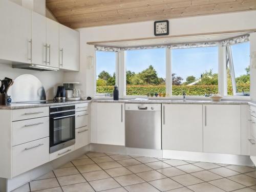 a kitchen with white cabinets and a large window at Holiday Home Asvalde - 200m to the inlet by Interhome in Vordingborg