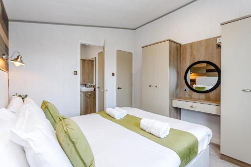 a bedroom with a large white bed and a mirror at Clumber Park Lodges in Worksop