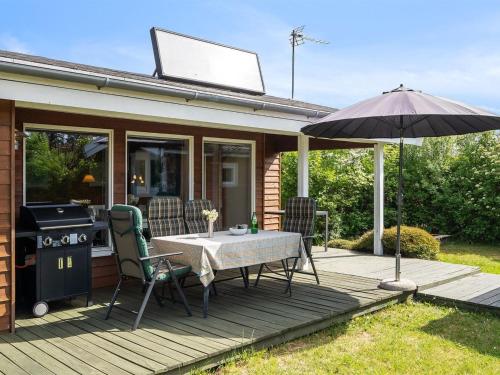 a wooden deck with a table and an umbrella at Holiday Home Felicity - 250m from the sea by Interhome in Karrebæksminde