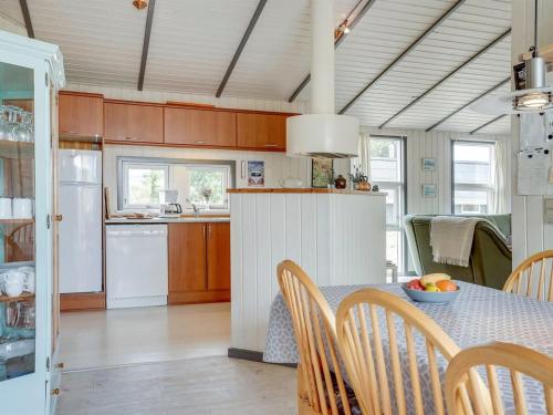 a kitchen with a table and chairs and a kitchen with a refrigerator at Holiday Home Floria - 1-4km from the sea by Interhome in Torsted