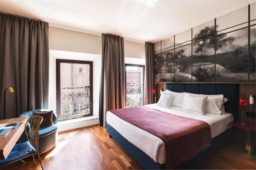 ein Hotelzimmer mit einem Bett, einem Schreibtisch und einem Fenster in der Unterkunft Casa D'Este - Hotel Ferrara in Ferrara
