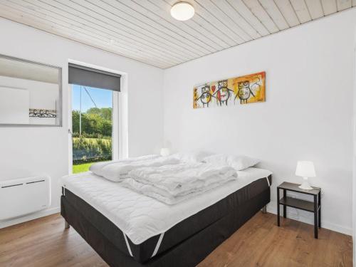 a white bedroom with a bed and a window at Holiday Home Ika - 450m from the sea by Interhome in Nordborg
