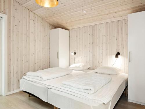 a bedroom with a large white bed with wooden walls at Holiday Home Heidel - 1-1km from the sea by Interhome in Nyrup