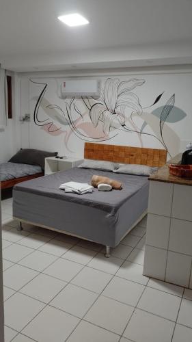 a bedroom with a bed with a painting on the wall at Temporada Ilheus na Praia dos Milionarios Kitnet in Ilhéus