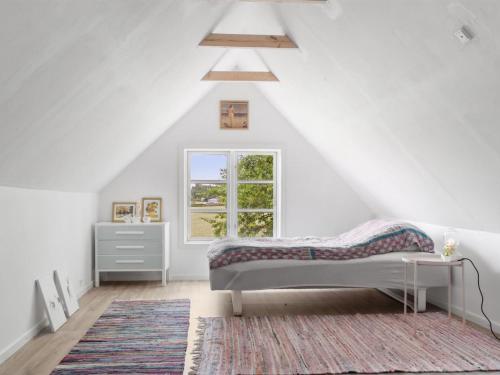 a white bedroom with a bed and a window at Holiday Home Finja - 6km from the sea by Interhome in Horslunde