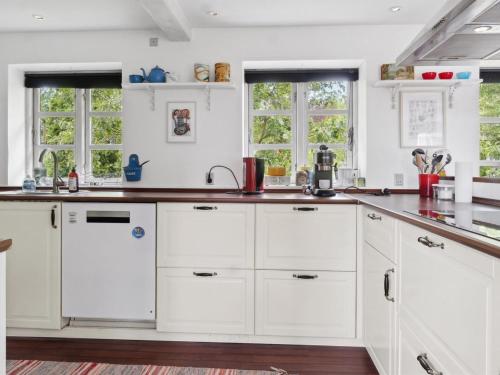 a white kitchen with white cabinets and windows at Holiday Home Finja - 6km from the sea by Interhome in Horslunde