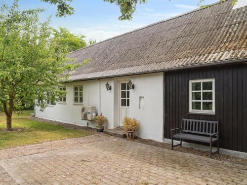 a white and black house with a bench in front of it at Holiday Home Finja - 6km from the sea by Interhome in Horslunde