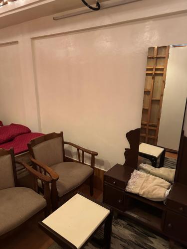 a living room with chairs and a mirror and shelves at Nupurs BnB in Shillong