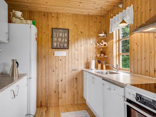 a kitchen with wooden walls and a white refrigerator at Holiday Home Rikhard - 75m from the sea by Interhome in Dannemare