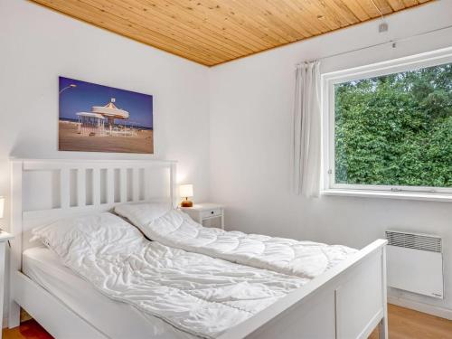 a white bed in a room with a window at Holiday Home Rikhard - 75m from the sea by Interhome in Dannemare