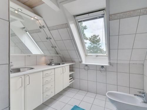 a white bathroom with two sinks and a window at Holiday Home Elisabetha - 16km from the sea by Interhome in Randbøl