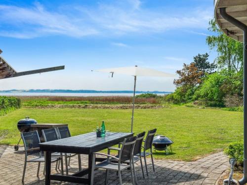 a wooden table with chairs and an umbrella at Holiday Home Vemund - 100m to the inlet by Interhome in Vig