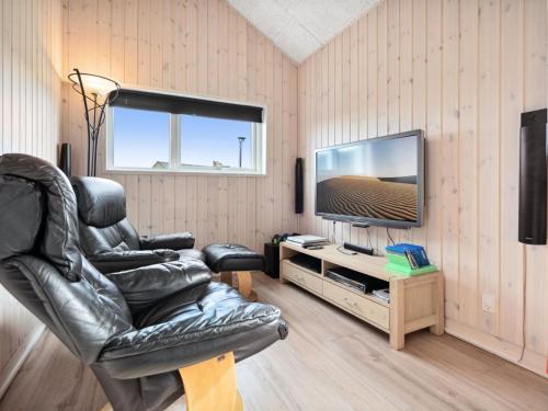 a living room with a black leather chair and a television at Holiday Home Amdi - 700m from the sea by Interhome in Neder Lysabild