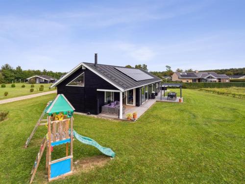 a black house with a slide and a playground at Holiday Home Amdi - 700m from the sea by Interhome in Neder Lysabild