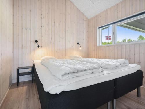 a bedroom with a bed with white sheets and a window at Holiday Home Amdi - 700m from the sea by Interhome in Neder Lysabild