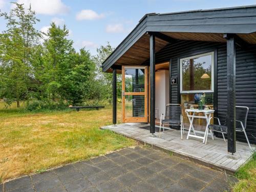 a black tiny house with a patio and a table at Holiday Home Fifi - 200m to the fjord by Interhome in Skjern