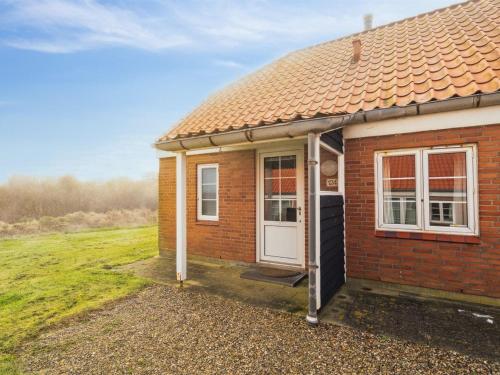 a small red brick house with a white door at Holiday Home Ubbe - 200m from the sea by Interhome in Lemvig