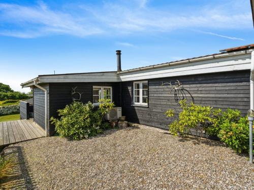 a black house with a gravel yard in front of it at Holiday Home Thrugils - 200m from the sea by Interhome in Haderslev