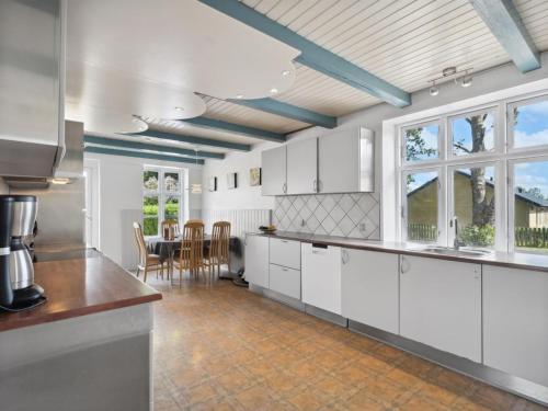 a large kitchen with white cabinets and a table at Holiday Home Essie - 20km from the sea by Interhome in Agerskov
