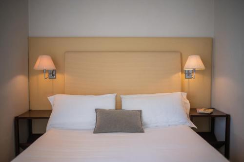 a bed with two white pillows and two lamps at Hotel Palazzo Cavalieri in Siracusa