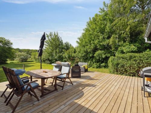a wooden deck with a table and chairs and an umbrella at Holiday Home Bjerne - 250m to the inlet by Interhome in Roslev