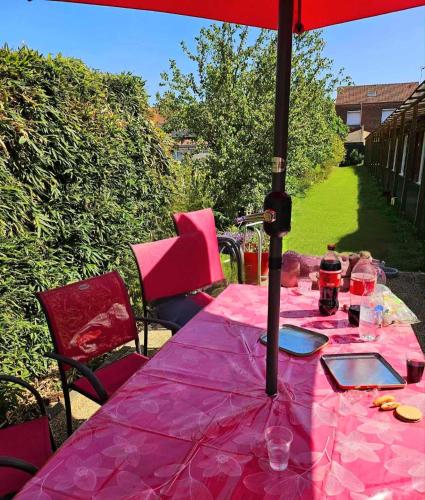 a pink table with an umbrella on a patio at Le Chti Paradis in Méricourt