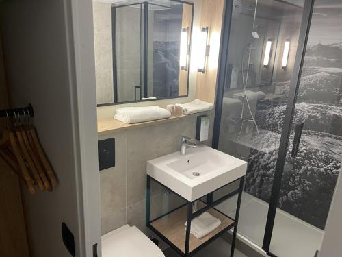 a bathroom with a white sink and a shower at Campanile NATURE - Clermont-Ferrand Nord Riom in Riom