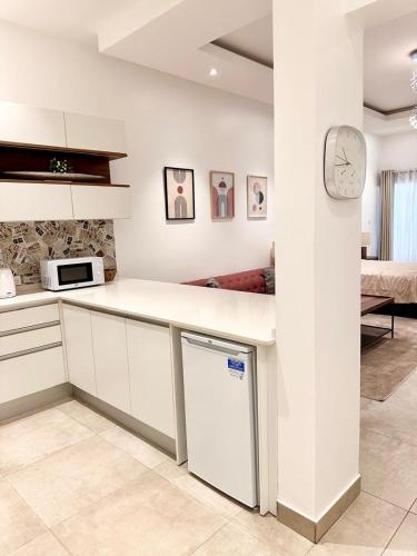 a white kitchen with a counter and a clock on a wall at Cozy, fully equipped apartment in Mermoz, Dakar in Dakar